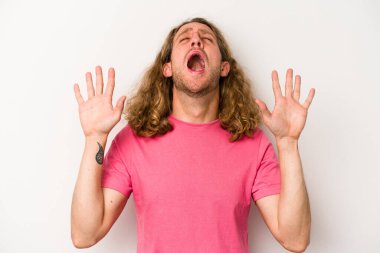 Beyaz arka planda izole edilmiş genç beyaz adam gökyüzüne haykırıyor, yukarı bakıyor, hayal kırıklığına uğramış..