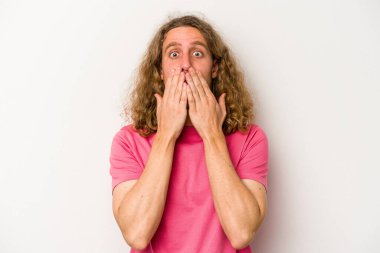 Beyaz arka planda izole edilmiş genç beyaz adam elleriyle ağzını kapatırken şok oldu..