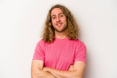 Beyaz arka planda kendini güvende hisseden, kararlılıkla kollarını kavuşturan beyaz tenli genç bir adam..