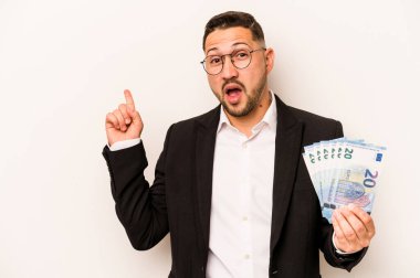 Hispanik adamın elinde banknotlar var. Beyaz arka planda izole edilmiş. Yan tarafı işaret ediyor.