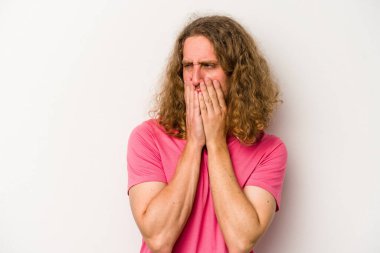 Beyaz arka planda izole olmuş genç beyaz bir adam bir şeye gülüyor, ağızlarını ellerle kapatıyor..