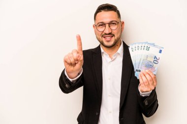 İspanyol bir adamın elinde banknotlar tutarken beyaz arka planda bir numara parmağıyla görünüyor..