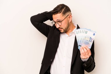 Beyaz arka planda izole edilmiş banknotlar tutan İspanyol bir adam kafasının arkasına dokunuyor, düşünüyor ve bir seçim yapıyor..
