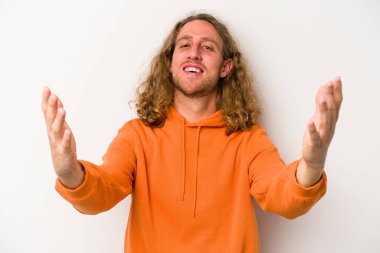 Beyaz arka planda izole olmuş genç beyaz bir adam zaferi veya başarıyı kutluyor, şaşırıyor ve şok oluyor..