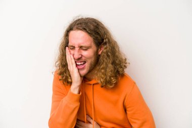 Beyaz arka planda izole genç beyaz adam mutlu bir şekilde gülüyor ve ellerini karnının üstünde tutarak eğleniyor..