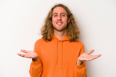 Beyaz arka planda izole genç beyaz adam kollarıyla ölçek yapar, mutlu ve kendinden emin hisseder..