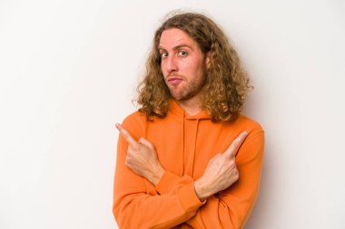 Beyaz arka plan noktalarında izole genç beyaz adam, iki seçenek arasında seçim yapmaya çalışıyor.