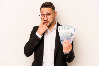 Beyaz arka planda, tırnak yiyen, gergin ve endişeli banknotlar tutan İspanyol bir adam..