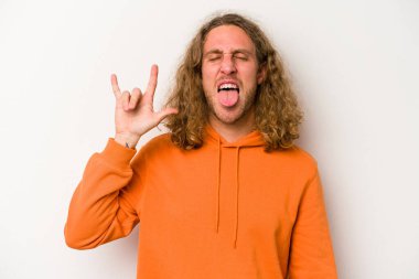 Beyaz arka planda izole edilmiş genç beyaz bir adam parmaklarıyla kaya hareketi gösteriyor.