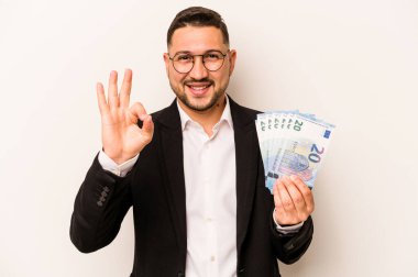 Hispanik adamın elinde banknotlar var. Beyaz arka planda izole edilmiş. Neşeli ve kendinden emin..