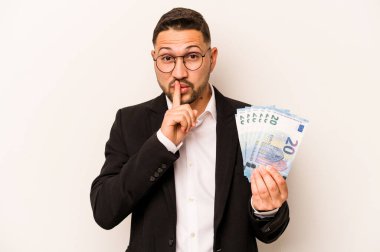 Hispanik adamın elinde banknotlar var. Beyaz arka planda izole edilmiş. Ya sır saklıyor ya da sessizlik istiyor..