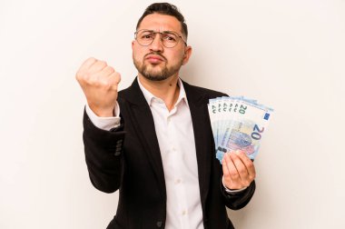 Beyaz arka planda izole edilmiş banknotlar tutan İspanyol bir adam yumruğunu kameraya gösteriyor, agresif bir yüz ifadesi..