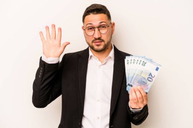 Beyaz arka planda izole edilmiş banknotları tutan İspanyol bir adam gülümseyerek beş numarayı parmaklarıyla gösteriyor..