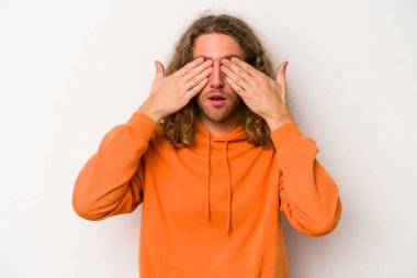 Beyaz arka planda izole edilmiş genç beyaz bir adam elleriyle gözlerini kapatmaktan korkuyor..