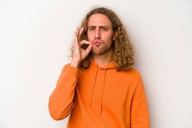 Beyaz arka planda izole edilmiş beyaz tenli genç bir adam parmakları dudaklarında bir sır saklıyor..