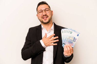 Beyaz arka planda izole edilmiş banknotları tutan İspanyol bir adam yüksek sesle gülüyor ve elini göğsüne koyuyor..