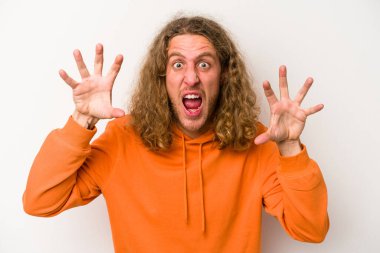 Beyaz arka planda izole edilmiş genç beyaz bir adam pençelerini kedi taklidi yaparken gösteriyor, agresif bir hareket..