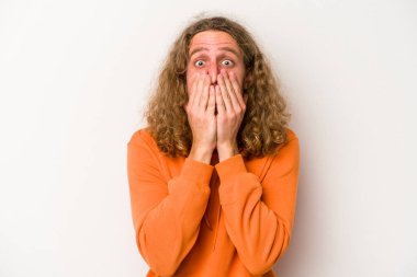 Beyaz arka planda izole edilmiş genç beyaz adam şok olmuş, ağzı ellerle kaplanmış, yeni bir şey keşfetmeye hevesli..