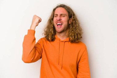 Beyaz arka planda izole edilmiş genç beyaz bir adam zaferi, tutkuyu ve coşkuyu kutluyor, mutlu bir ifade..