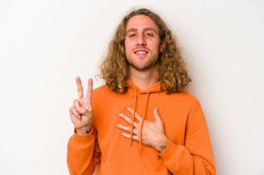 Beyaz arka planda izole edilmiş genç beyaz adam yemin ediyor, elini göğsüne koyuyor..