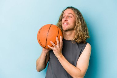 Beyazların basketbol oynayan genç adamı mavi arka planda izole edilmiş.