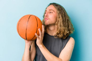 Beyazların basketbol oynayan genç adamı mavi arka planda izole edilmiş.