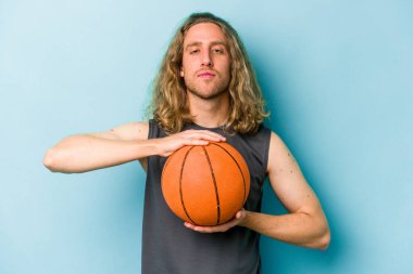 Beyazların basketbol oynayan genç adamı mavi arka planda izole edilmiş.