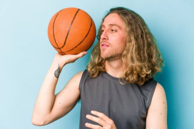 Beyazların basketbol oynayan genç adamı mavi arka planda izole edilmiş.
