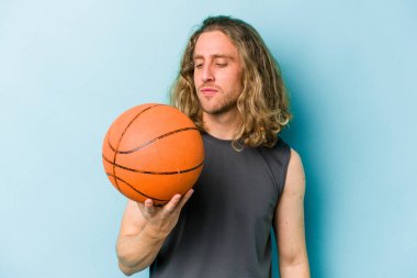Beyazların basketbol oynayan genç adamı mavi arka planda izole edilmiş.