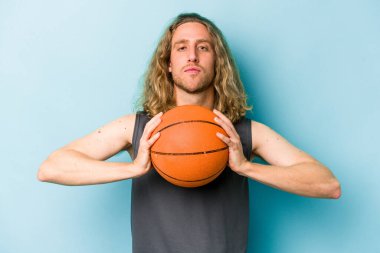Beyazların basketbol oynayan genç adamı mavi arka planda izole edilmiş.