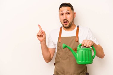 Bahçıvan İspanyol bir adam elinde su bidonu tutarken beyaz arka planda izole edilmiş bir şekilde kenarı işaret ediyor.