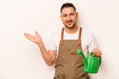 Bahçıvan İspanyol bir adam beyaz arka planda izole edilmiş bir su bidonu tutuyor bir avuç içinde fotokopi alanı ve belinde başka bir el tutuyor..