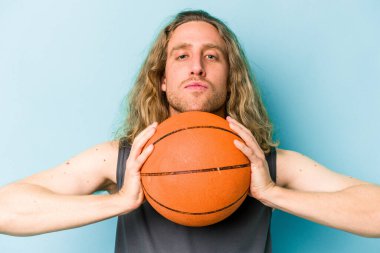 Beyazların basketbol oynayan genç adamı mavi arka planda izole edilmiş.