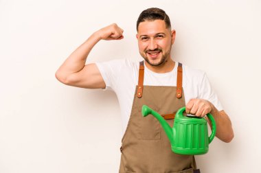 Bahçıvan İspanyol bir adam beyaz arka planda izole edilmiş bir su bidonu tutuyor zaferden sonra yumruğunu kaldırıyor, kazanan konsept.