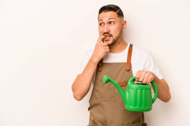 Bahçıvan İspanyol bir adam beyaz arka planda izole edilmiş bir su bidonu tutuyor. Bir şeyin fotokopi odasına baktığını düşünüyor..