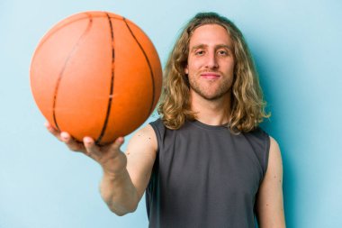 Beyazların basketbol oynayan genç adamı mavi arka planda izole edilmiş.