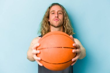 Beyazların basketbol oynayan genç adamı mavi arka planda izole edilmiş.