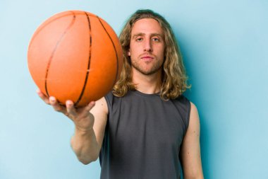 Beyazların basketbol oynayan genç adamı mavi arka planda izole edilmiş.