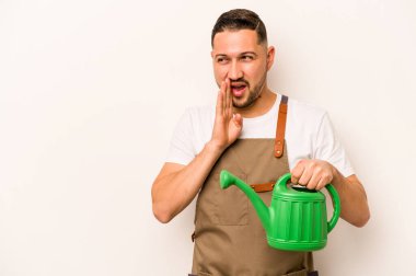 Bahçıvan İspanyol bir adam beyaz arka planda izole bir su bidonu tutuyor gizli bir sıcak fren haberi söylüyor ve yana bakıyor