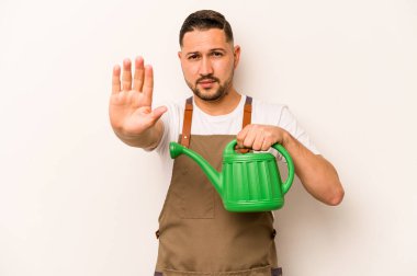 Bahçıvan İspanyol bir adam, beyaz arka planda izole edilmiş bir su bidonu tutuyor elini uzatmış, dur işaretini gösteriyor ve seni engelliyor..
