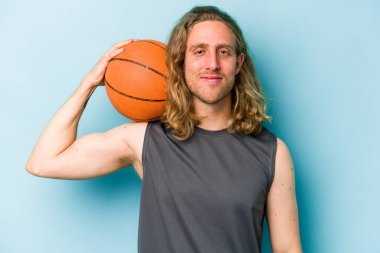 Beyazların basketbol oynayan genç adamı mavi arka planda izole edilmiş.