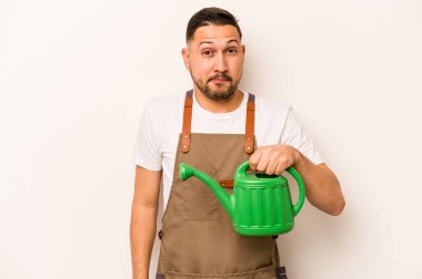 Bahçıvan İspanyol bir adamın elinde su kovası var. Beyaz arka planda izole edilmiş. Kafası karışmış, şüpheci ve kararsız..