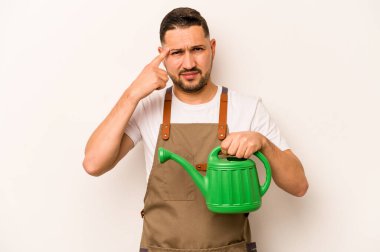 Bahçıvan İspanyol bir adam beyaz arka planda izole bir su bidonu tutuyor işaret parmağıyla bir hayal kırıklığı jesti gösteriyor.