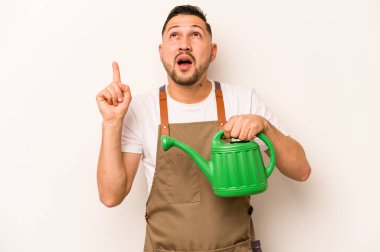 Bahçıvan İspanyol bir adam, beyaz arka planda izole edilmiş bir su bidonu tutuyor ve ağzı açık bir şekilde yukarı bakıyor..