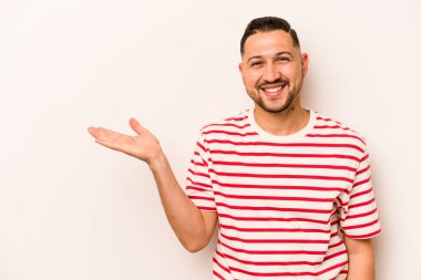 Beyaz arka planda izole edilmiş genç İspanyol bir adam bir avuç içinde fotokopi alanı ve belinde bir el daha gösteriyor..