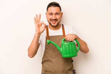 Bahçıvan İspanyol bir adam beyaz arka planda izole edilmiş bir su bidonu tutuyor. Neşeli ve kendinden emin..