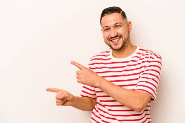 Beyaz arka planda izole edilmiş genç bir İspanyol işaret parmaklarıyla işaret ederek heyecanlanıyor..