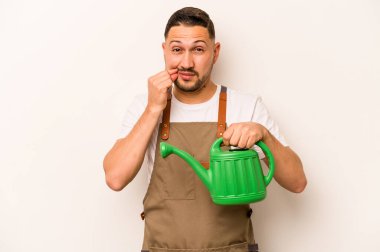 Bahçıvan İspanyol bir adam su bidonu tutuyor beyaz arka planda izole edilmiş parmakları dudaklarında bir sır saklıyor.