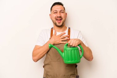 Bahçıvan İspanyol bir adam beyaz arka planda izole bir su bidonu tutuyor kahkahalar atıyor elini göğsüne koyuyor.