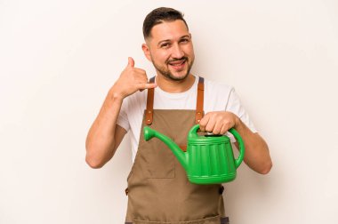 Bahçıvan İspanyol bir adam beyaz arka planda izole edilmiş bir su bidonu tutuyor. Cep telefonu hareketini parmaklarıyla gösteriyor..